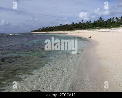 Ein ruhiger Sandstrand mit großen Felsen an der Küste Stockfoto