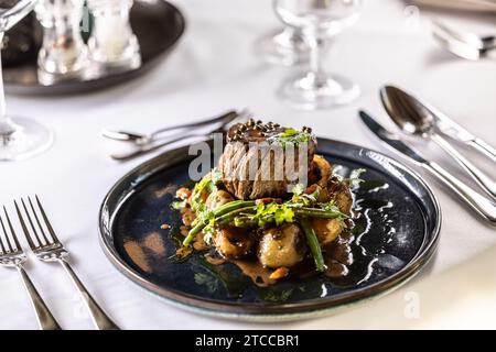 Filet-Steak aus Rinderfilet, sautierte grüne Bohnen mit Speck, gebackene Kartoffeln und grüne Pfeffersoße. Filet Steak serviert auf einem Teller auf einem fest Stockfoto