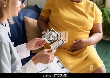 Nahaufnahme einer Krankenschwester, die Ultraschallbild des Babys untersucht und mit schwangeren Frauen gesprochen hat Stockfoto