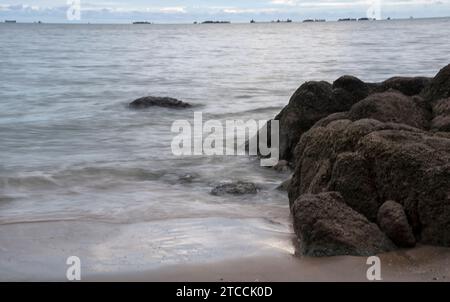 Langsame Aufnahmen der Meereswellen entlang des felsigen Strandes. Stockfoto