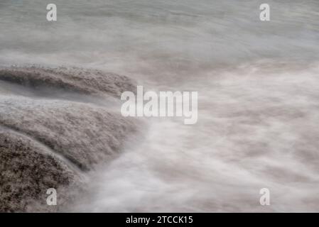 Langsame Aufnahmen der Meereswellen entlang des felsigen Strandes. Stockfoto