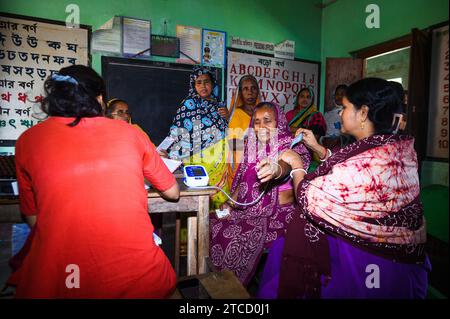 Nabin Nagar, ein Dorf an der Grenze zwischen Indien und Bangladesch, ist schlecht verbunden und isoliert von der Hauptstadt Tehatta, Indien. Deshalb wurde von der Regierung des Bundesstaates Westbengalen ein Lager eingerichtet, in dem die Dorfbewohner Medikamente verteilen konnten, nachdem sie Aadhaar-Karten durch einen medizinischen Offizier gezeigt hatten und mit Hilfe von asha-Arbeitern kostenlose Untersuchungen zur Blutdruckkontrolle an der Nabin Nagar-Grundschule durchgeführt hatten. An diesem Tag kommen alle armen Dorfbewohner, von den Ältesten bis zu den Schülern, zu einer kostenlosen medizinischen Untersuchung in Nabin Nagar, Westbengalen, Indien. Stockfoto