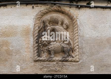 Das Basrelief aus Stein zeigt den Kampf zwischen einem Wolf, einem Adler und einem Löwen im mittelalterlichen Dorf Finalborgo, Finale Ligure, Savona, Ligurien, Italien Stockfoto