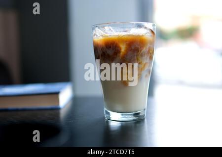 Ein großes transparentes Glas gefüllt mit kaltem Sommergetränk mit Eiswürfeln ist auf einem grauen, isolierten Hintergrund fotografiert, Foto für das Menü. Hohe Qualität Stockfoto