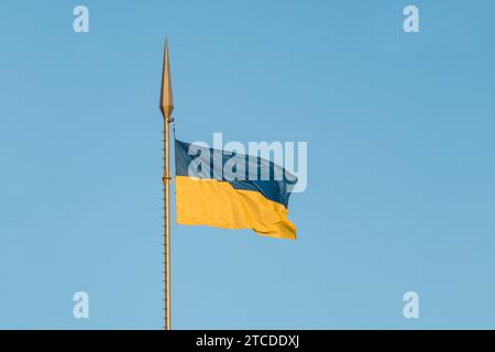 Die Nationalflagge der Ukraine flattert im Wind auf einem hohen Fahnenmast im Sonnenuntergang Stockfoto