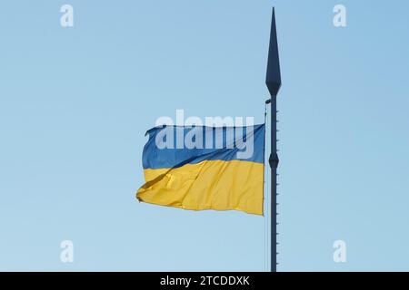 Die Nationalflagge der Ukraine flattert im Wind auf einem hohen Fahnenmast im Sonnenlicht Stockfoto