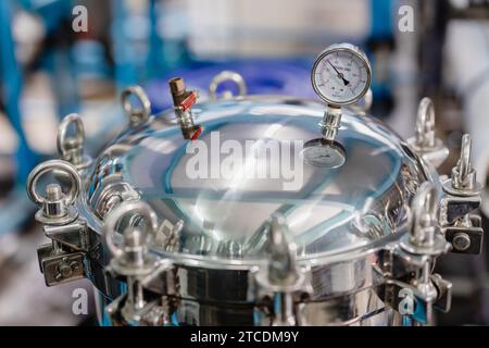 Verschlussdeckel Des Druckbehälters Verriegelt. Edelstahl Sanitärbehälter Mit Rundem Mannloch-Türdeckel, Schloss Mit Manometer In Der Industrie Fabrik. Stockfoto