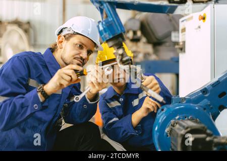 Reparaturservice für Mitarbeiter des Technikteams Ersetzen Sie defekte Teile des Schweißarms des automatischen Industrieroboters. Personal repariert Wartung Roboter Schweißmaschine. Stockfoto