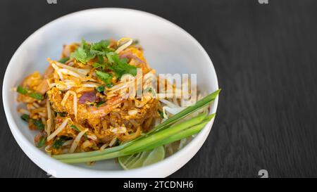 Pad thai Koriander oben saftig cremig lecker köstlich weltweit beliebt. Berühmte thailändische Essenskarte in der Schüssel auf schwarzem Holztisch. Stockfoto