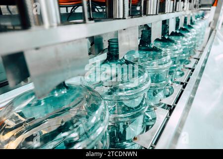 PET-Trinkwasser-Gallonenflasche aus Kunststoff sauber in der Förderband-Produktionslinie in der Trinkwasserfabrik. Stockfoto