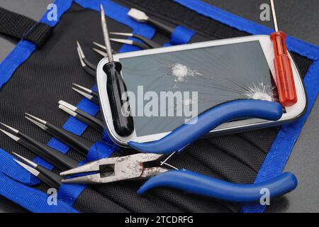 Mobilgerät mit defektem Display, Euro und Tools, Symbolbildkosten für Mobilgeräte Stockfoto