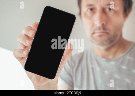 Mann, der ein Handy hält, mit leerem schwarzen Bildschirm als Kopierraum, selektiver Fokus Stockfoto