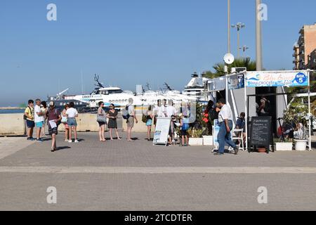 Touristen, die im Hafen von Trapani anstehen, um Tickets für eine Tagesfahrt mit Blu Lines zu den Inseln Favignana und Levanzo zu kaufen Stockfoto