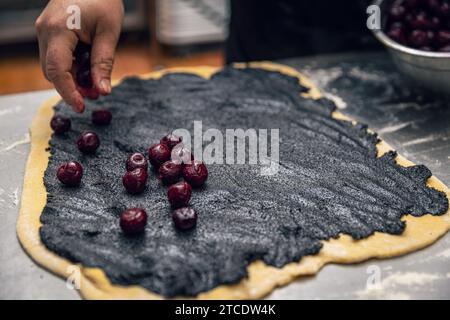 Bäckereiprozess. Zubereitung von süßem Brötchen oder Babka mit Mohn und Kirsche. Stockfoto