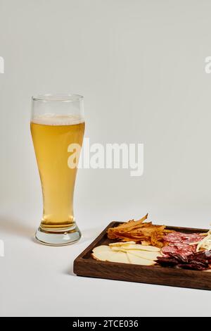 Ein Glas Craft-Bier in der Nähe der Wurstplatte mit Käseauswahl, getrocknetem Rindfleisch und Salami auf Grau Stockfoto