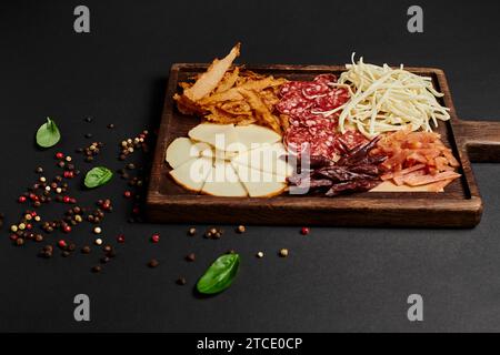 Blick von oben auf Wurstplatte mit Käseauswahl, getrocknetem Rindfleisch und Salami auf schwarzem, Antipasto Stockfoto