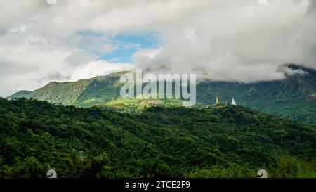 Wunderschöne Landschaft. Blick von oben auf die wunderschöne weiße buddha-Statue mit hinter Berg und Wald am Wat Phra That Pha Son Kaew, Khao Kho Phetchab Stockfoto