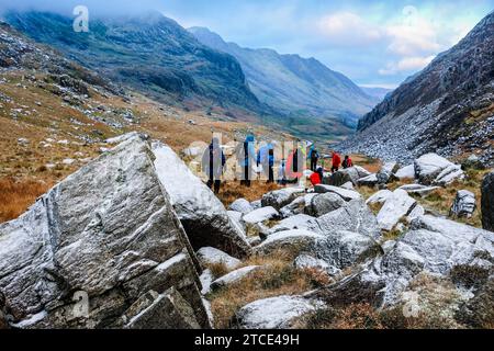 Gruppe von Wanderern, die im Winter den Llanberis Pass im Snowdonia National Park vom Pen-Y-Pass, Llanberis, Gwynedd, Nordwales, Großbritannien, hinunterlaufen, Großbritannien Stockfoto