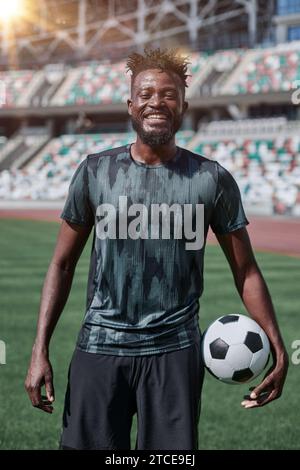 Ein junger Mann steht in einem Stadion mit einem Fußball in der Hand Stockfoto