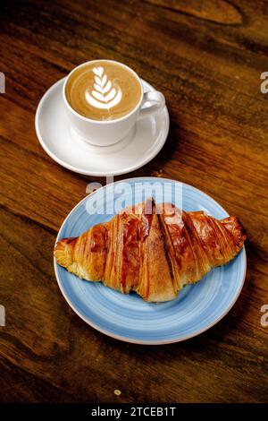 Frisch gebackenes Croissant mit Kaffee auf Holztisch Stockfoto