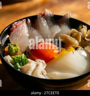 Japanische Sashimi Donburi mit Weißfisch, Tintenfisch und Eigelb auf einem Bett aus weißem Reis. Stockfoto