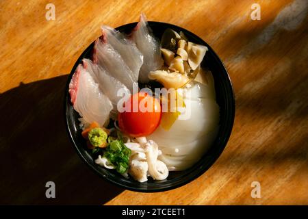 Japanische Sashimi Donburi mit Weißfisch, Tintenfisch und Eigelb auf einem Bett aus weißem Reis. Stockfoto