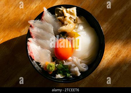 Japanische Sashimi Donburi mit Weißfisch, Tintenfisch und Eigelb auf einem Bett aus weißem Reis. Stockfoto