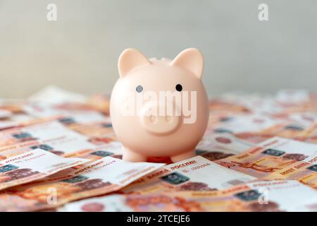 Rosa Schweinebank mit russischen Banknoten Währungsrubel im Nominalwert von fünftausend. Das Konzept des Sparens und Anhäufens von Geld. Stockfoto