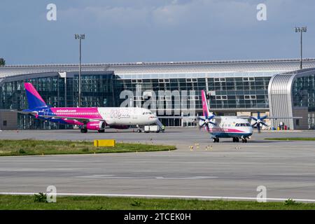 Motor sich Antonov an-140 fährt zum Start von Lemberg für einen Flug nach Kiew mit WizzAir Airbus A320 im Hintergrund Stockfoto