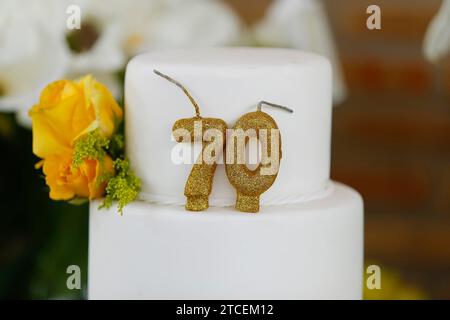 Detail der Zahl siebzig oben auf dem Geburtstagskuchen, 70 Geburtstag, weißer Kuchen, 70 Jahre alte Geburtstagskuchen Kerze Stockfoto