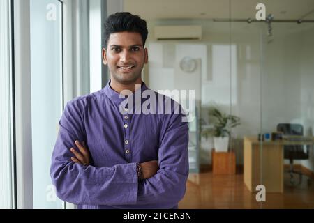 Porträt eines indischen Geschäftsmannes in Kurta, der Arme kreuzt und in die Kamera lächelt Stockfoto