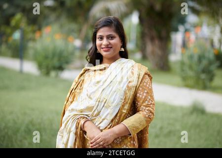 Porträt einer Indianerin im gelben Sari-Kleid, die an einer Hochzeit im Freien teilnimmt Stockfoto