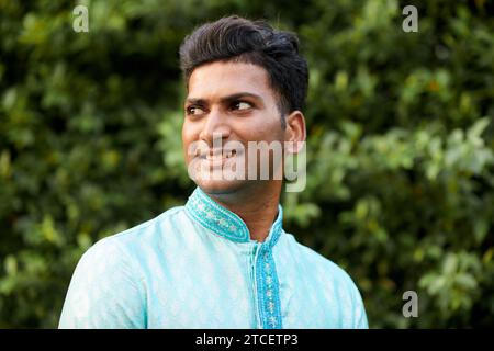Porträt eines lächelnden jungen Indianers, der im Park steht und wegblickt Stockfoto