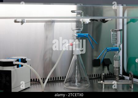 Leerer Arbeitsplatz im biochemischen Labor. Laborglas und Vakuumpumpe auf Edelstahltisch. Selektiver Fokus. Stockfoto