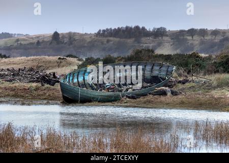 Ein verlassenes hölzernes Fischerboot auf den Sanddünen in der Mündung des Flusses Esk, St Cyrus, Aberdeenshire, Schottland Stockfoto