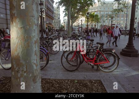 Ein paar geparkte Fahrräder in Barcelona und Touristen, die auf einer veru geschäftigen Straße namens Rambla vorbeifahren Stockfoto