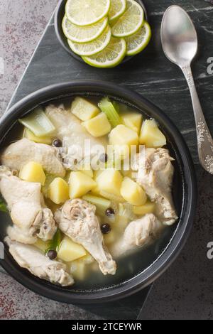 Bahama Hühnersouse ist ein Geflügelgericht mit Hühnerflügel, Zwiebeln, Kartoffeln, Sellerie, Limettensaft, Allspiz-Nahaufnahme auf dem Teller auf dem Tisch. Ve Stockfoto