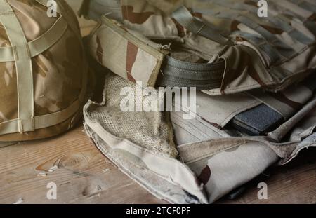 Ein Militärhelm eines ukrainischen Soldaten mit einer schweren kugelsicheren Weste auf einem Holztisch im Innenraum des Kontrollpunktes Stockfoto