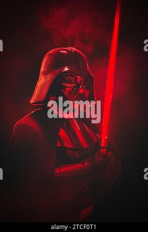 NEC, BIRMINGHAM, GROSSBRITANNIEN - 3. DEZEMBER 2023. Ein männliches Cosplay bei einem Comic-Concept-Event in Darth Vader Kostüm aus Star Wars mit einem roten Lichtschwert in einem Drama Stockfoto