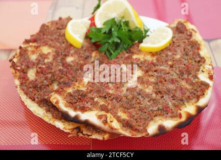 Teller mit Lahmacun, einer dünnen und knusprigen türkischen Pizza, gekrönt mit gewürztem Hackfleisch Stockfoto
