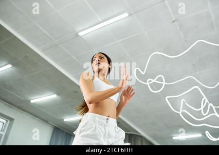 Niedrigwinkelansicht einer temperamentvollen afroamerikanerin in weißer Sportswear, die im Studio Proben Stockfoto