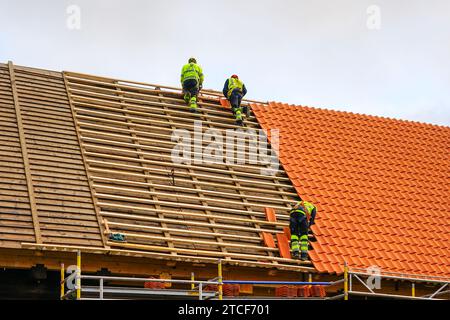 Austausch von Tonziegeldächern, drei Arbeiter legen neues Tonziegeldach Stockfoto