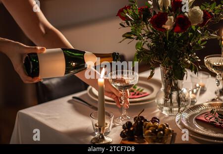 Champagner wird von der Flasche zum Glas auf dem Tisch gegossen Stockfoto