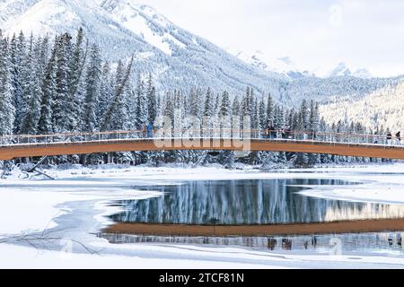 Fußgängerbrücke in Banff über den Bow River mit Reflexionen im Winter Stockfoto