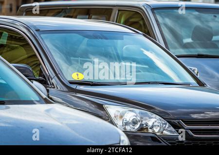 Kleiner gelber Aufkleber für Anfänger an der Windschutzscheibe eines geparkten Autos. Stockfoto