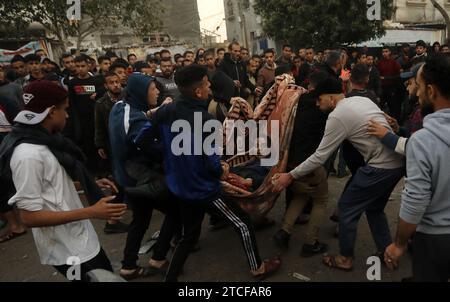 Rafah, Gaza. Dezember 2023. Palästinenser tragen einen Verletzten nach dem israelischen Bombardement im Flüchtlingslager Al-Shaboura in Rafah im südlichen Gazastreifen Dienstag, 12. Dezember 2023. Berichten zufolge wurden bei dem Bombenanschlag Israels in Rafah am Dienstag mindestens 22 Menschen getötet, darunter sieben Kinder. Die weltweiten Forderungen nach einem Waffenstillstand wurden von Israel und den Vereinigten Staaten ignoriert, da die humanitären Hilfsmaßnahmen zusammengebrochen sind und vor Hunger und Krankheit in der Bevölkerung des Gazastreifens warnten. Foto: Ismael Mohamad/UPI Credit: UPI/Alamy Live News Stockfoto