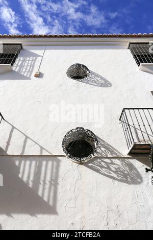 Runde Fenster mit schmiedeeisernem Gitter an weiß getünchter Fassade in Ronda, Malaga, Spanien Stockfoto