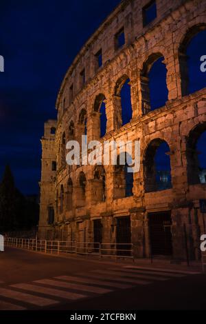 Vertikaler Blick auf die Pula Arena mit Quersteg bei Nacht. Römisches Amphitheater in Kroatien am Abend. Stockfoto