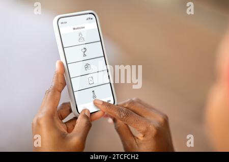 afroamerikanerin, die zu Hause Telemedizin-App auf dem Smartphone durchsucht Stockfoto