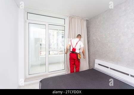 Arbeiter im einheitlich hängenden Fenstervorhang in Innenräumen Stockfoto